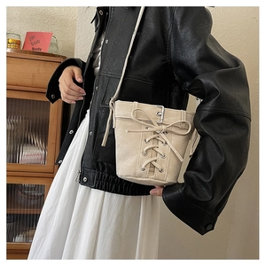 Gros plan détaillé d'un sac seau en toile beige avec nœud décoratif et boucles en métal