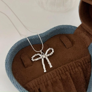 Minimalist 925 sterling silver bow pendant necklace on a vintage jewelry box