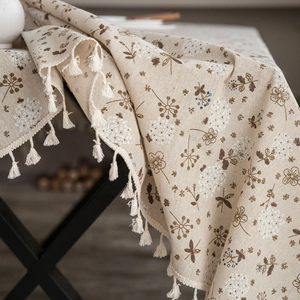 Detailed macro view of cotton linen tablecloth featuring floral prints and fringe edges