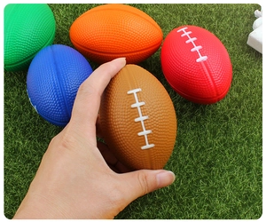 Close-up of colorful mini PU foam footballs being held above a green turf background