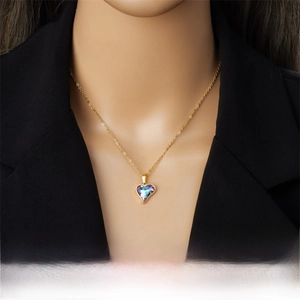 Gros plan d'un pendentif cœur dégradé violet et bleu sur une chaîne dorée porté par un mannequin
