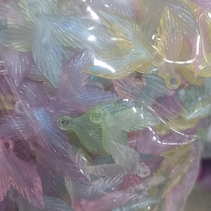 Close-up of glittery luminous acrylic fishtail pendants in bulk transparent packaging