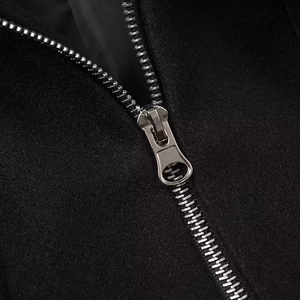 Close-up of a silver metal zipper on a black wool jacket featuring professional stitching