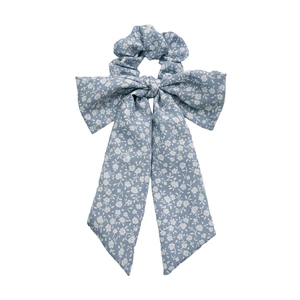Blue floral fabric scrunchie with a large bow tie knot on a clean white background