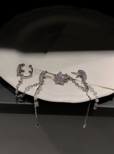 Macro view of elegant silver star and moon tassel earrings with pearls on a white plate