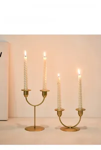 Close-up of dual-head golden iron candle holders with elegant spiral white candles