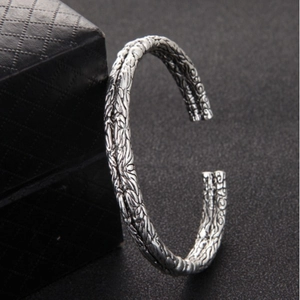 Vintage silver open bangle for men with detailed relief engravings on a black jewelry box
