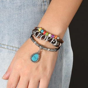 Multilayer leather bracelet with turquoise pendant and love charm on denim background