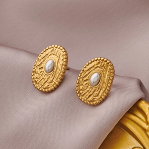 Detail of vintage gold oval stud earrings with pearl on a purple silk fabric