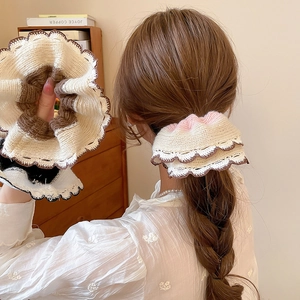 Knitted lace scrunchie in beige and brown colors shown on hair and held by hand