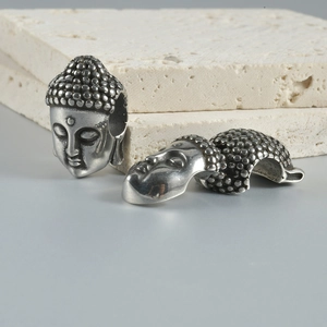 Macro shot of Buddha-style metal spacer beads with vintage silver finish and detailed carving