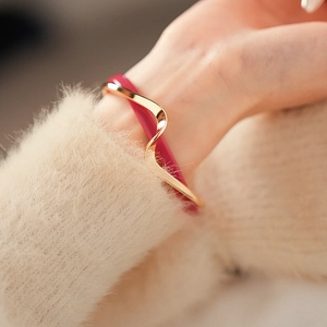 Close-up of a wavy gold and rose red double-layer geometric cuff bracelet on a model