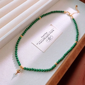 Detail of malachite bead necklace with gold star pendant on jewelry display tray