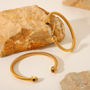 Twisted C-shaped gold stainless steel bracelet with blue and brown gemstone details