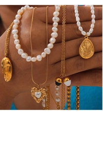 Detail of layered gold necklaces with freshwater pearls and vintage heart pendants