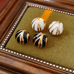 Detailed view of round enamel earrings with gold stripes on green velvet base