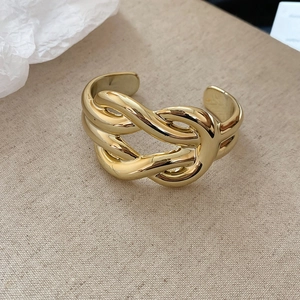 Macro detail of gold irregular textured bracelet with a horseshoe buckle on linen fabric