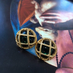 Boucles d'oreilles vintage dorées avec gemmes émail vert sur fond de livre d'art