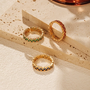 Detail of adjustable gold rings with colorful zircon hearts on a beige stone plate