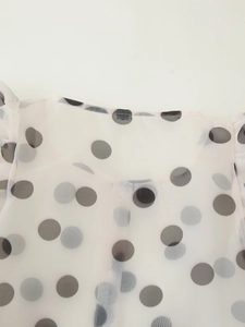 Detail shot of sheer white organza shirt collar with bold black polka dot pattern