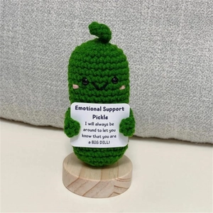 Close-up of handmade crochet emotional support pickle on a round wooden base