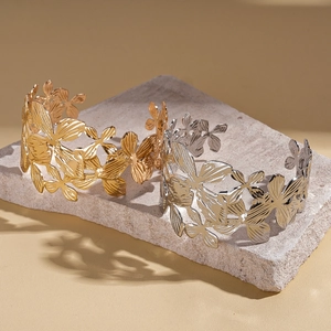 Artistic cutout orchid bangles in gold and silver finish on a stone pedestal