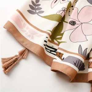Detailed macro view of tropical floral print scarf with elegant brown fringe tassels