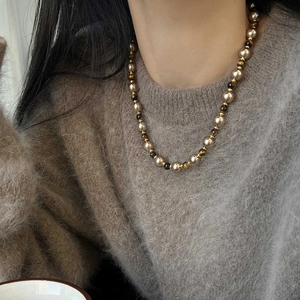 Collier de perles dorées champagne vintage avec oeil de tigre sur pull en laine grise