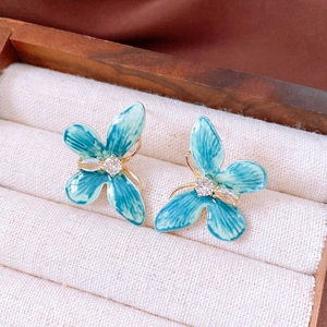 Détail macro de boucles d'oreilles papillon en émail bleu avec pierres blanches et écrin