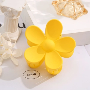 Macro view of a yellow flower hair claw clip on a minimalist aesthetic background