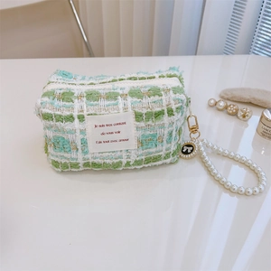 Close-up of green tweed handbag with pearl handle and bow charm detail