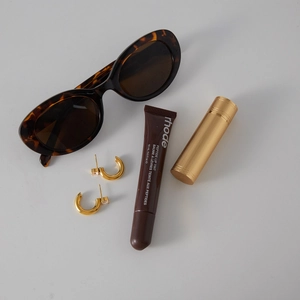 Detailansicht der goldenen C-Ohrringe mit Zirkonia-Steinen im Lifestyle-Setting