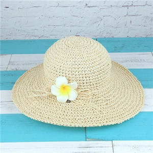 Close-up of woven straw hat featuring decorative plumeria flower and jute rope detail