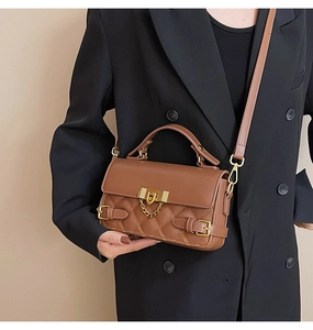 Detail of brown quilted shoulder bag with gold metal clasp and adjustable strap