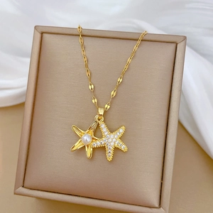 Close-up of golden starfish necklace with pearl inlay and crystals on silk background