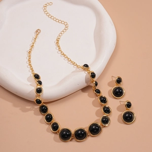 Vintage gold necklace and earring set with black resin round pendants on stone