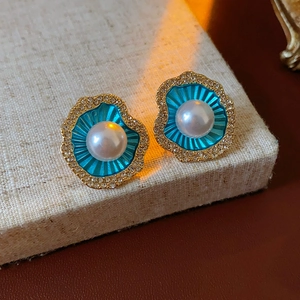 Détail des boucles d'oreilles coquillage doré avec émail bleu et petites perles blanches