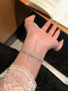 Detail of 18K gold plated bracelet featuring zircon flowers and square links on wrist
