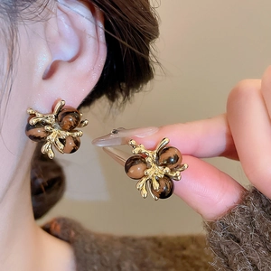 Close-up of vintage golden earrings featuring brown tiger eye beads in a floral design