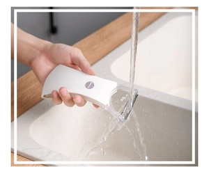 Washable stainless steel vegetable peeler being rinsed under water in a kitchen