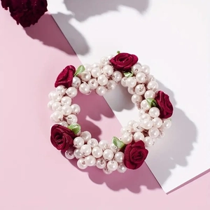 French style hair scrunchie with white pearls and vintage red fabric roses on pink background