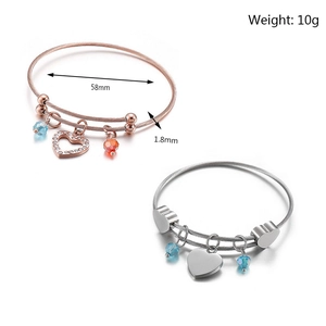 Detail of rose gold and silver braided steel bracelets with heart charms and beads