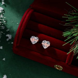 Close-up of heart-shaped earrings with rose gold ribbons in a red velvet jewelry box