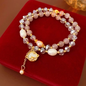 Bracelet double rang en perles et cristal avec pendentif Saturne doré sur velours rouge