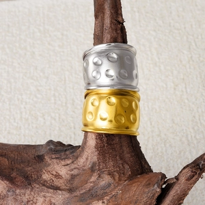 Détail de bagues géométriques larges en or et argent avec texture martelée sur branche