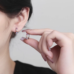 Silver geometric hoop earrings with colorful cubic zirconia stones on model and hand