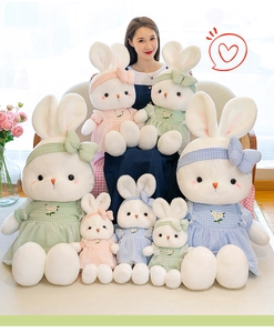 Various sizes of plush toy rabbits wearing floral embroidered plaid dresses in soft colors