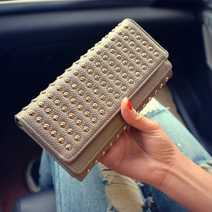 Dettaglio della pochette in pelle kaki con rivetti dorati mostrata in un contesto di vita