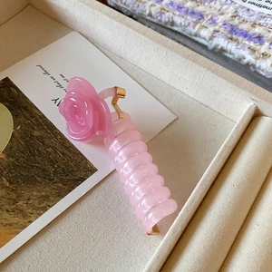 Détail d'une pince à cheveux fleur en résine rose translucide avec ressort doré