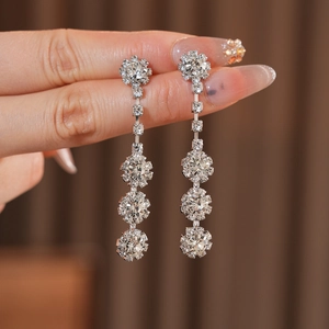 Close-up of silver long-drop earrings with sparkling circular diamond-set floral pendants